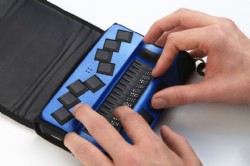Lnea braille de 16 celdas en color azul con funda negra y dos manos leyendo