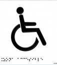 Persona en silla de ruedas en color negro, con fondo en blanco y con braille