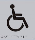 Persona en silla de ruedas en color negro, con fondo en gris y con braille