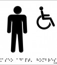 Una persona de pie y otra en silla de ruedas en negro con fondo en aluminio blanco y braille