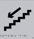 Escaleras con flecha hacia abajo en negro sobre fondo gris