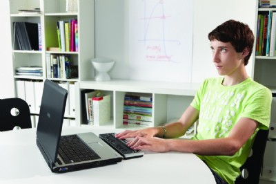 Un joven manejando la línea braille delante de un PC